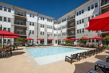 a swimming pool with chaise lounge chairs and umbrellas in front of an apartment building at Marley EAV, Atlanta, GA, 30316